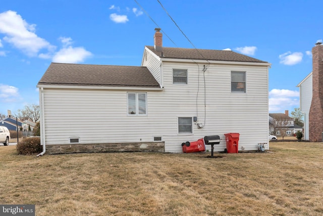 back of property with a shingled roof, a lawn, and a chimney