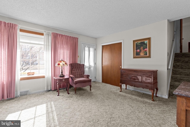 sitting room featuring carpet flooring, visible vents, stairway, and a textured ceiling