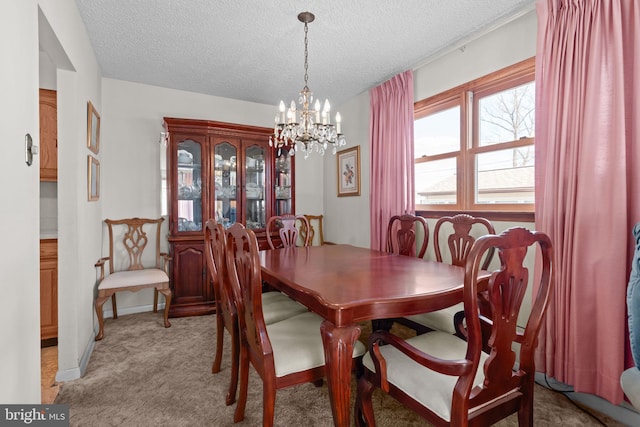 dining space with a textured ceiling, baseboards, light colored carpet, and an inviting chandelier