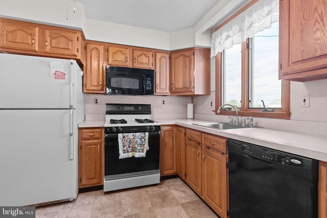 kitchen featuring black appliances, a sink, light countertops, and brown cabinets