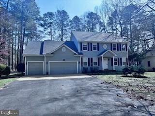 colonial house with aphalt driveway and an attached garage