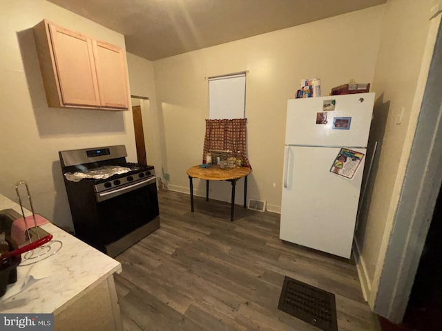 kitchen with visible vents, dark wood finished floors, freestanding refrigerator, light countertops, and stainless steel range with gas cooktop