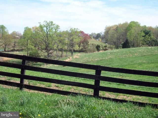 view of gate featuring a yard, a rural view, and fence