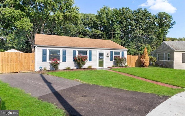 view of front of house with driveway, fence, and a front lawn