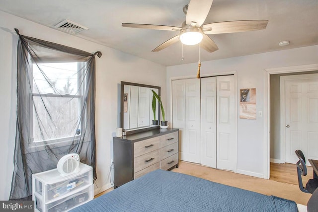 bedroom featuring light carpet, visible vents, baseboards, a ceiling fan, and a closet