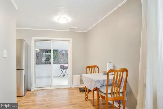 dining space with visible vents, ornamental molding, and wood finished floors