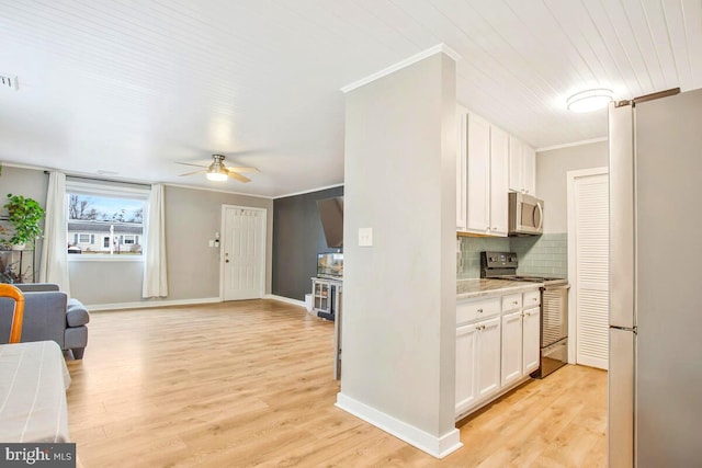 kitchen with stainless steel appliances, white cabinets, light countertops, ornamental molding, and tasteful backsplash