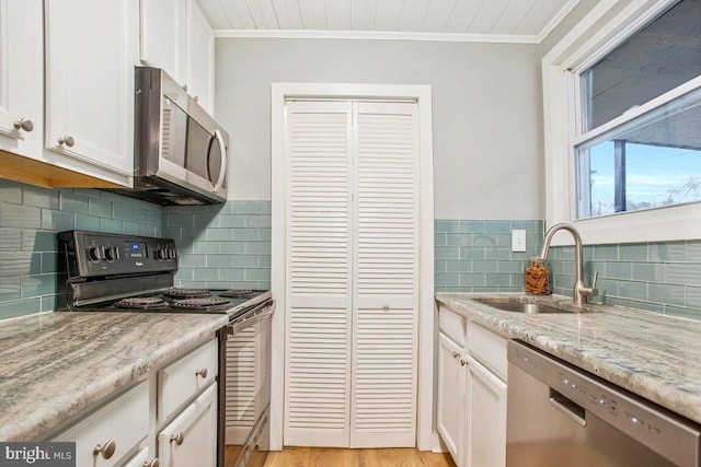 kitchen with appliances with stainless steel finishes, white cabinets, a sink, and ornamental molding