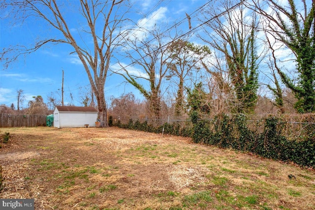 view of yard with a storage shed, a fenced backyard, and an outbuilding