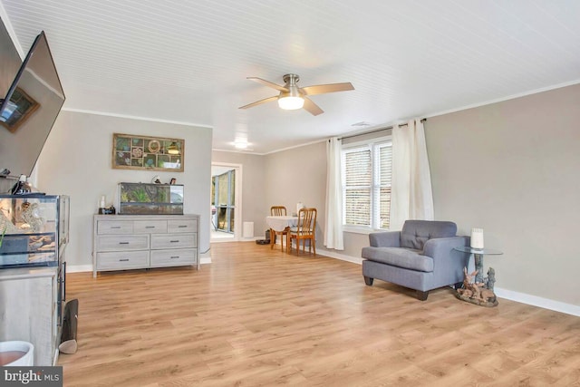 living area with baseboards, ornamental molding, a ceiling fan, and light wood-style floors