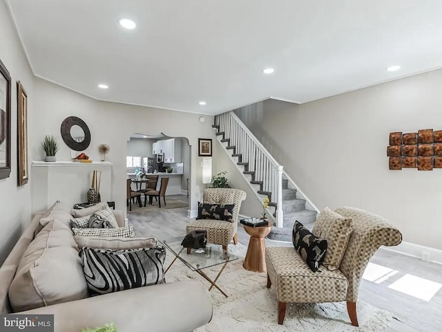 living area featuring stairway, arched walkways, wood finished floors, and recessed lighting