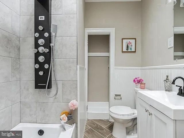 bathroom with toilet, a bathing tub, a wainscoted wall, vanity, and a shower