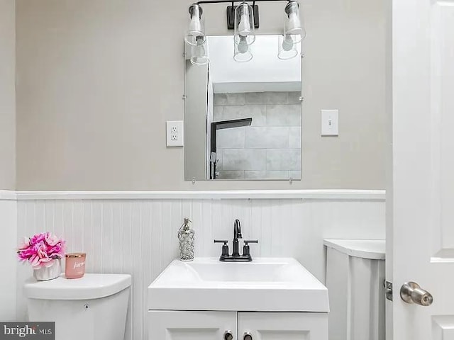 bathroom with wainscoting, vanity, and toilet