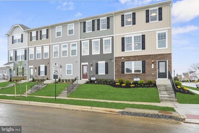 multi unit property featuring a front yard and brick siding