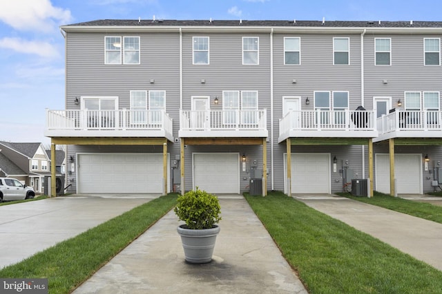 rear view of house featuring an attached garage, driveway, and central AC unit