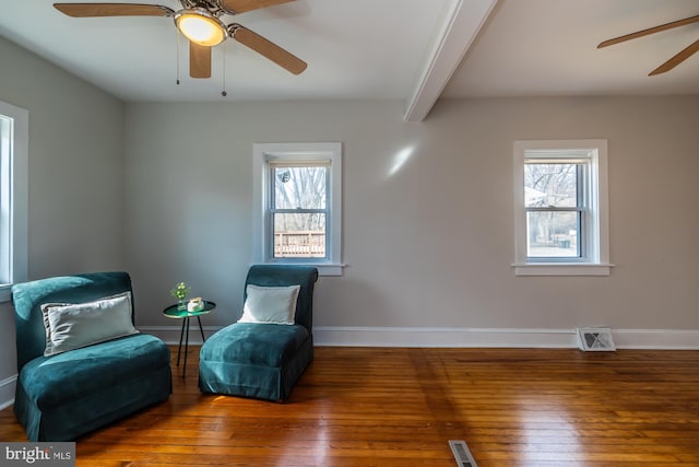 living area featuring a healthy amount of sunlight, visible vents, and beam ceiling