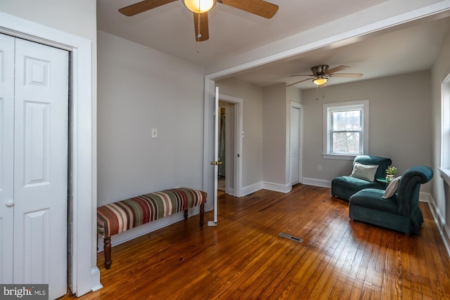 living area featuring a ceiling fan, visible vents, baseboards, and hardwood / wood-style floors