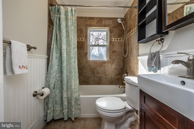 full bathroom with wainscoting, toilet, shower / bathtub combination with curtain, tile patterned flooring, and vanity