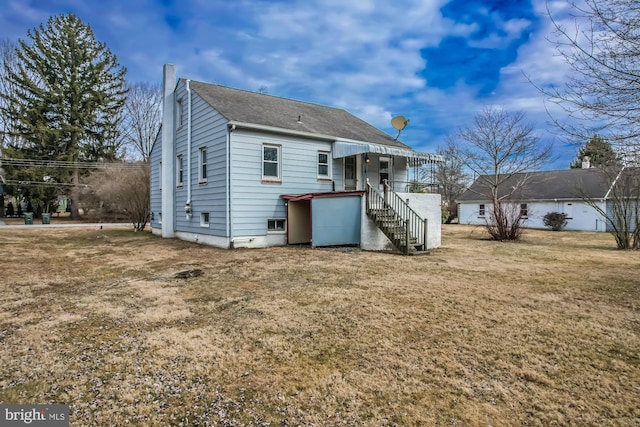 back of property with a yard, a shingled roof, and a chimney