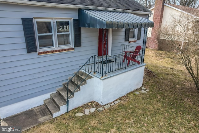 view of exterior entry featuring a shingled roof