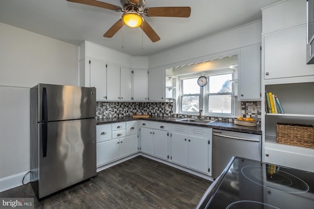 kitchen with dark wood-style floors, dark countertops, decorative backsplash, appliances with stainless steel finishes, and a sink