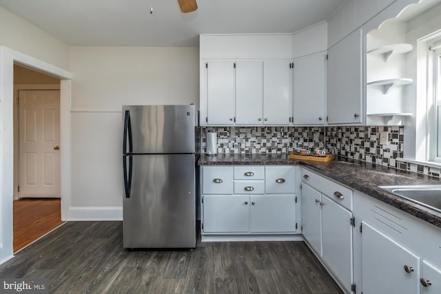 kitchen featuring dark wood-type flooring, freestanding refrigerator, open shelves, tasteful backsplash, and dark countertops