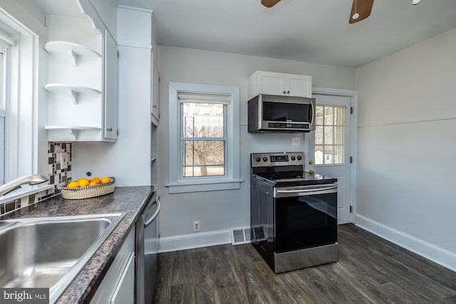 kitchen with dark countertops, dark wood-style flooring, stainless steel appliances, white cabinetry, and a sink