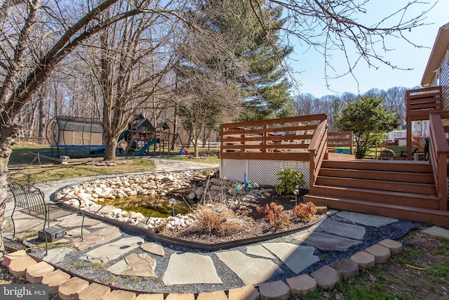 view of yard with a trampoline, a playground, and a wooden deck