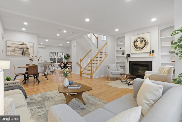 living room featuring built in features, stairway, wood finished floors, and recessed lighting