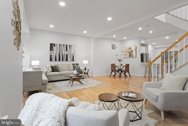 living area with recessed lighting, baseboards, stairs, and light wood finished floors