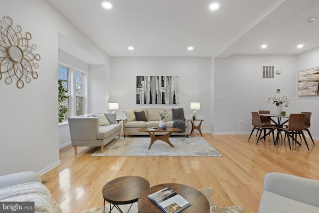 living room featuring recessed lighting, baseboards, and light wood finished floors