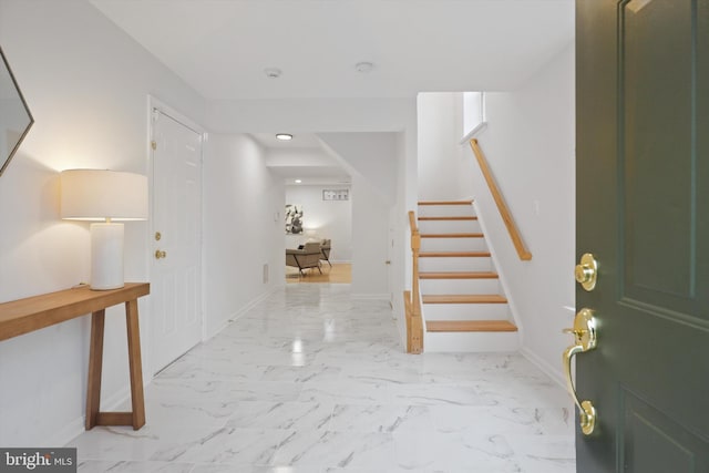 foyer entrance featuring stairs, baseboards, and marble finish floor