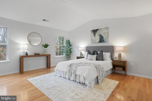 bedroom with visible vents, lofted ceiling, baseboards, and wood finished floors