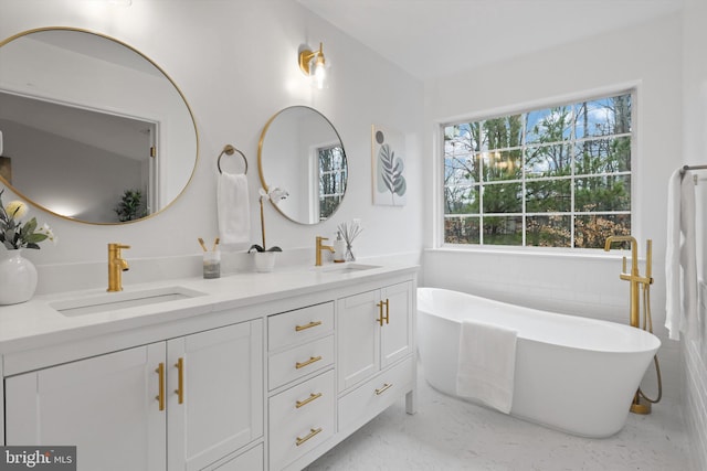 full bathroom featuring a sink, a soaking tub, and double vanity