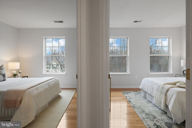 bedroom with visible vents, light wood-type flooring, and baseboards