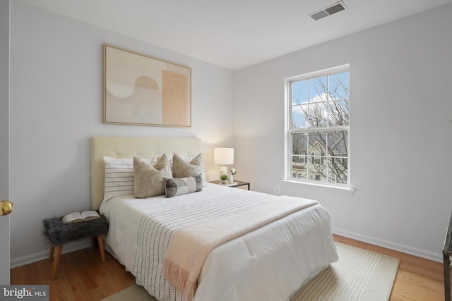 bedroom featuring wood finished floors, visible vents, and baseboards