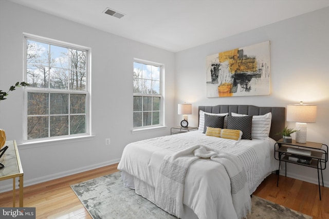 bedroom with visible vents, baseboards, and wood finished floors