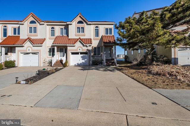 view of front facade featuring a tile roof, a garage, driveway, and stucco siding