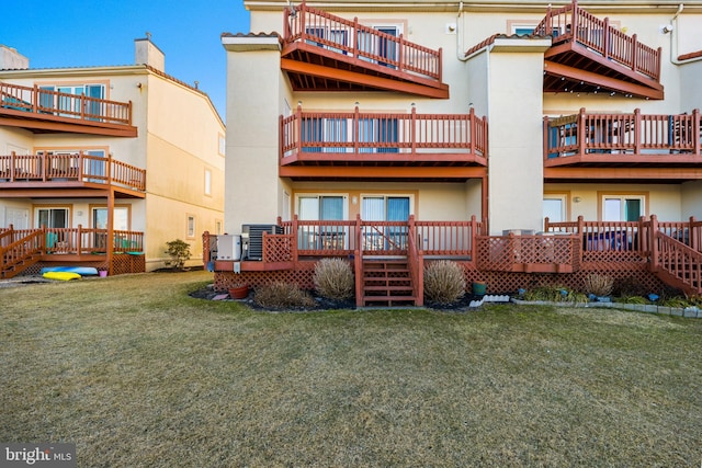 rear view of property featuring a lawn and stucco siding