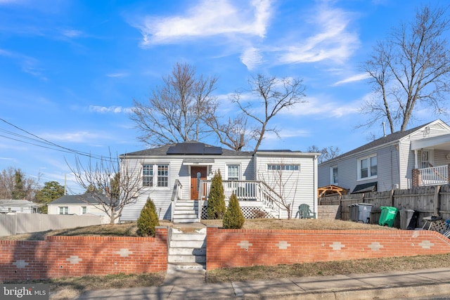 view of front of house featuring roof mounted solar panels and fence