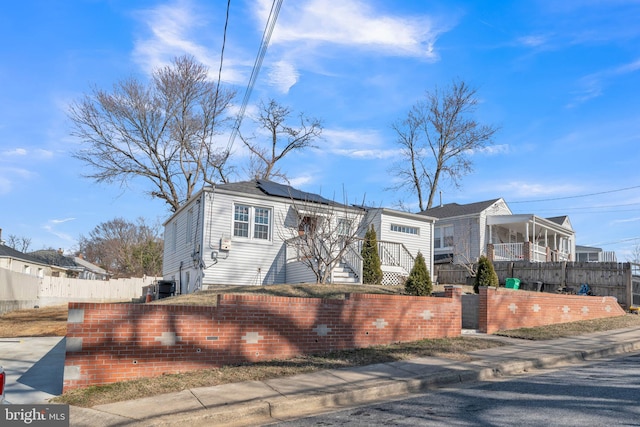 view of front of home featuring solar panels, central AC unit, and a fenced front yard