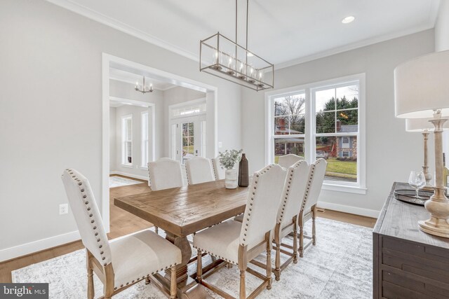 dining space featuring baseboards, ornamental molding, and light wood-style floors