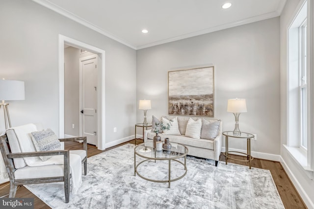 living area with ornamental molding, wood finished floors, and baseboards