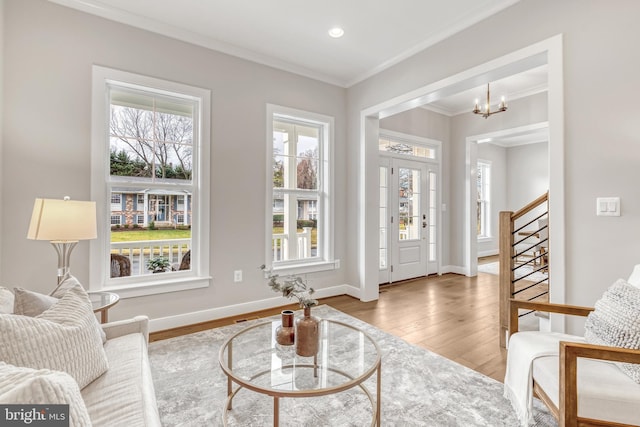 living area featuring wood finished floors, baseboards, ornamental molding, stairway, and an inviting chandelier