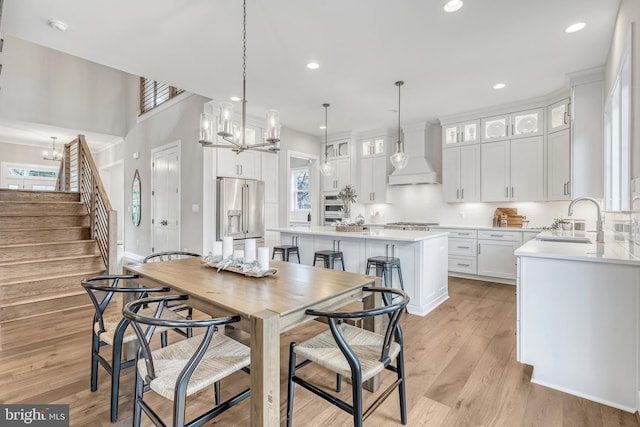 dining area featuring baseboards, stairs, light wood-type flooring, a chandelier, and recessed lighting