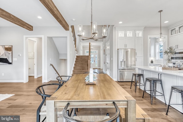 dining area featuring a wealth of natural light, beam ceiling, light wood-style flooring, and an inviting chandelier