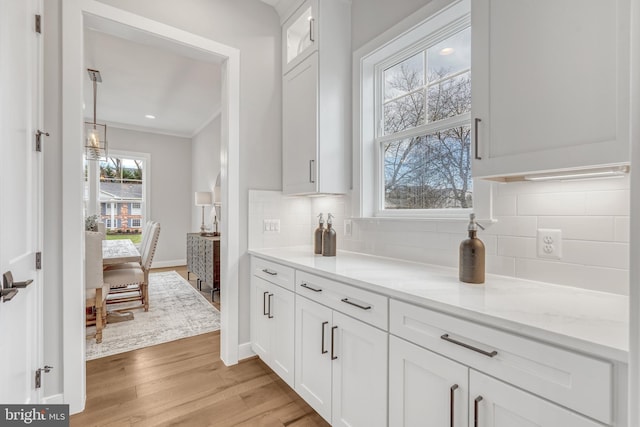 bar featuring baseboards, crown molding, light wood-style floors, backsplash, and recessed lighting