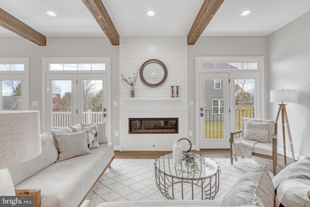 living area featuring recessed lighting, a large fireplace, light wood-type flooring, beamed ceiling, and baseboards