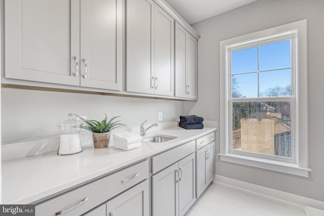 kitchen featuring light countertops, a sink, and baseboards