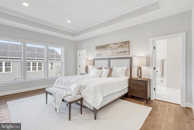 bedroom featuring hardwood / wood-style flooring, baseboards, a tray ceiling, and recessed lighting